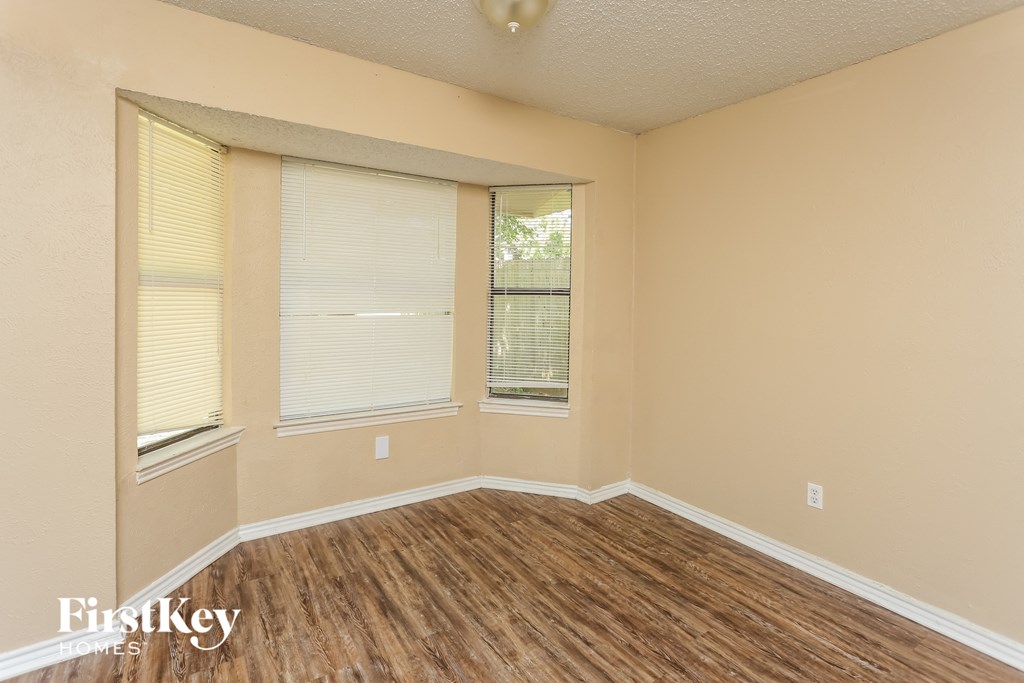 the living room of an empty home with wood flooring and two windows