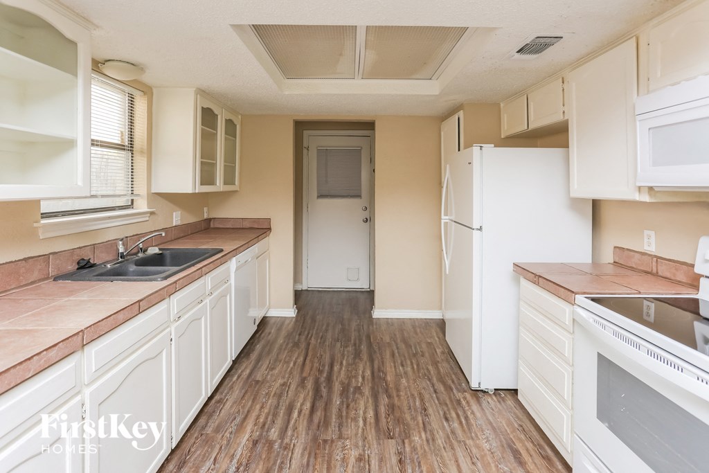 a kitchen with white cabinets and a sink and a refrigerator