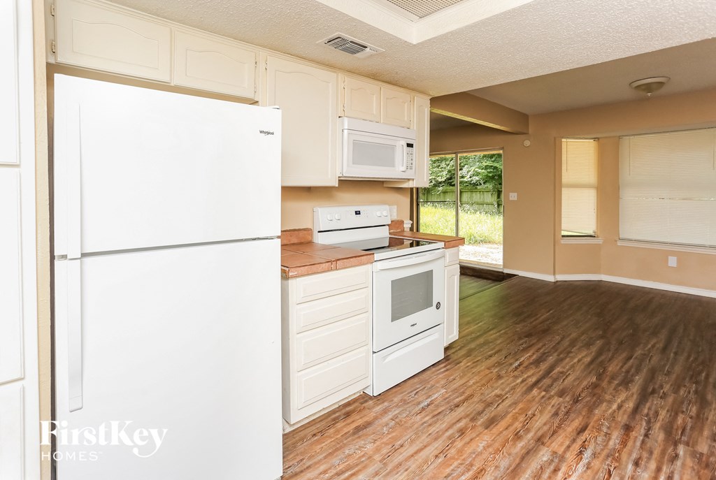 a kitchen with white appliances and a wooden floor