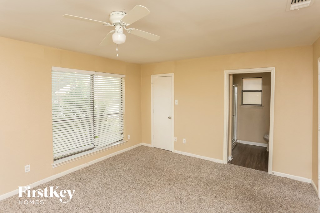 an empty living room with a ceiling fan and a large window