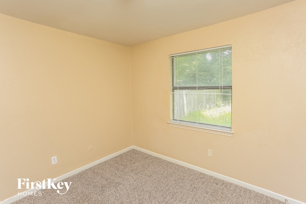 the upstairs bedroom has a large window and beige carpet