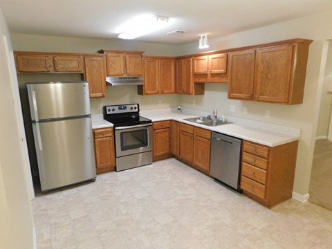 an empty kitchen with wooden cabinets and stainless steel appliances