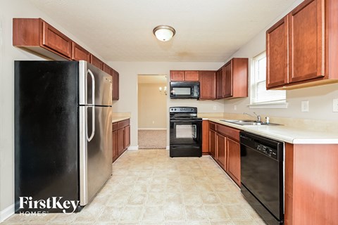 A kitchen with a black fridge and wooden cabinets.