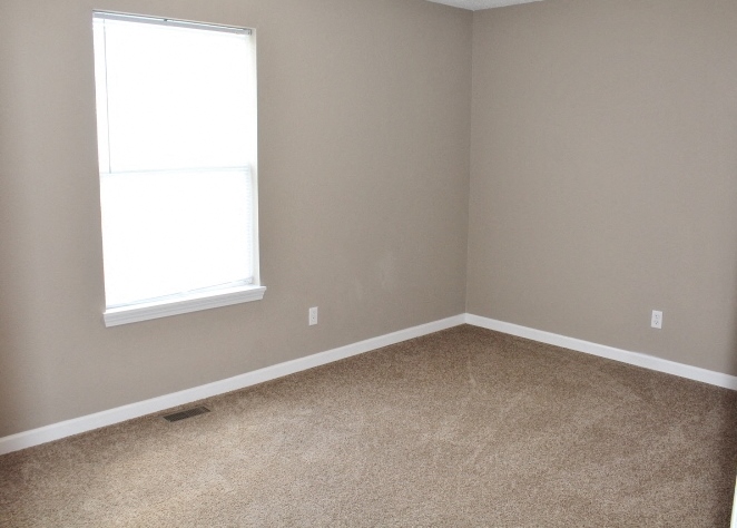 an empty room with a window and carpet