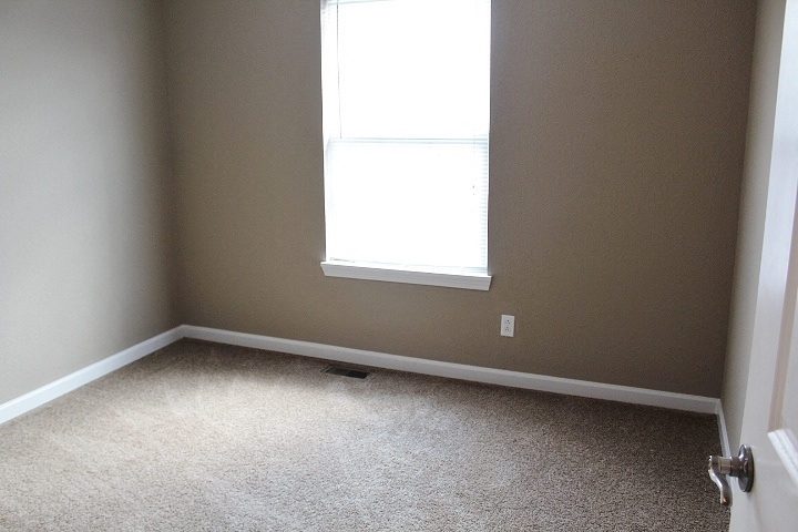 an empty room with a window and a carpet