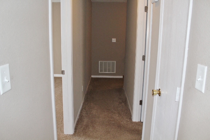 a hallway with a carpeted floor and an open door