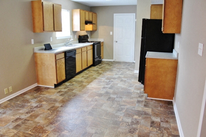 a kitchen with wooden cabinets and a black refrigerator