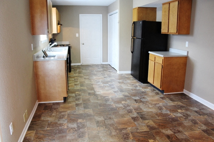 a kitchen with wooden cabinets and a black refrigerator