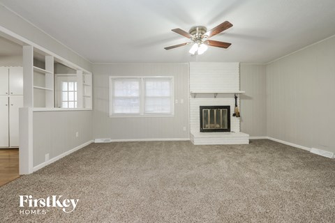 A spacious living room with a fireplace and a ceiling fan.