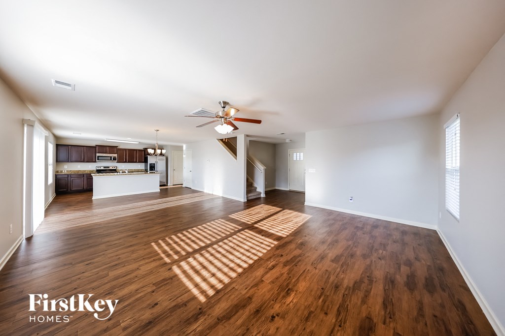 an open living room and kitchen with hardwood flooring and a ceiling fan