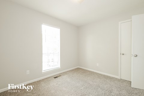 a bedroom with white walls and carpet and a door
