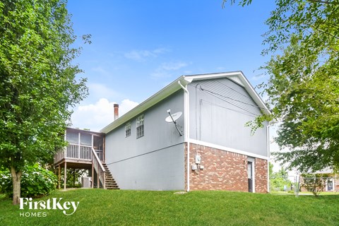 a white and brick house on a hill with trees