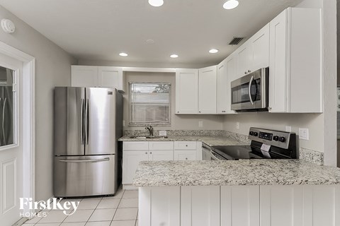 a white kitchen with white cabinets and a stainless steel refrigerator