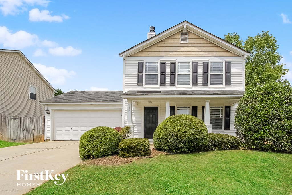 a white house with black shuttered windows and a lawn