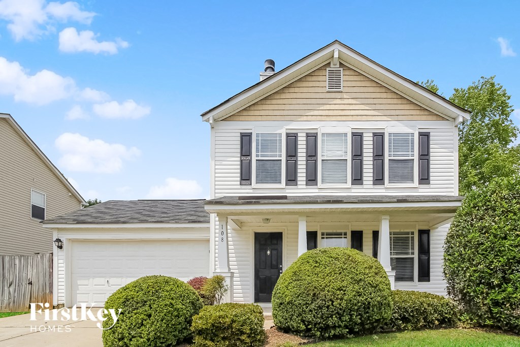 a white house with white shutters and a yard with bushes