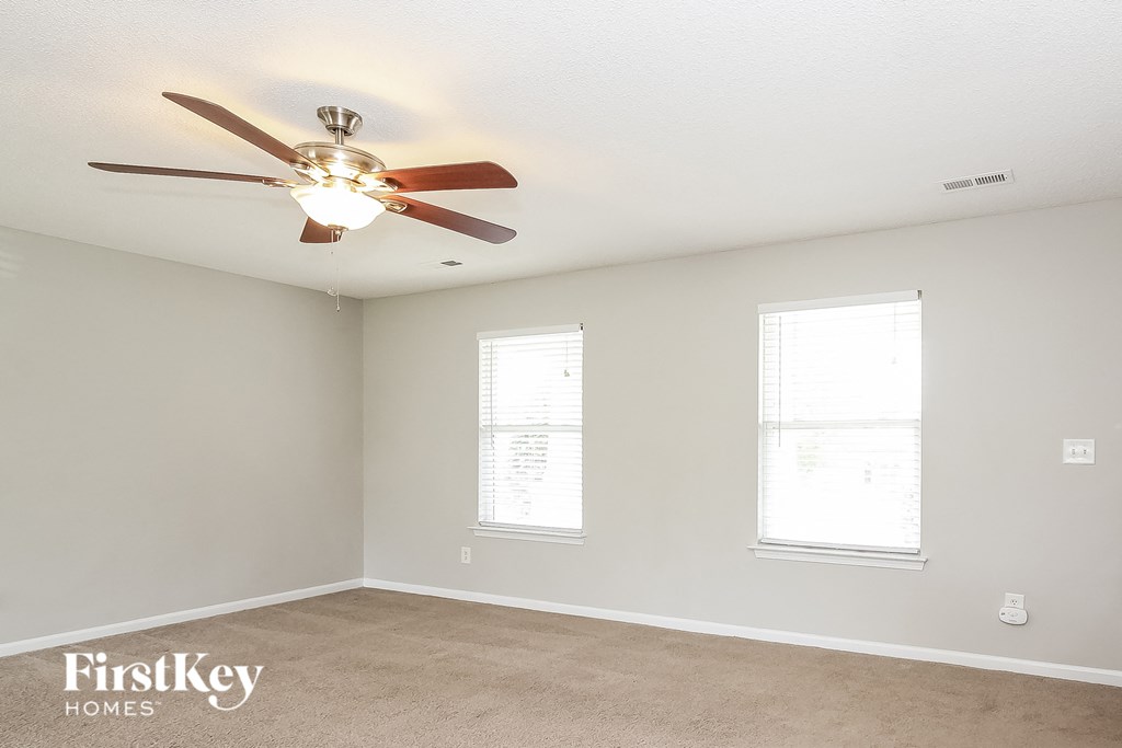 a bedroom with a ceiling fan and two windows