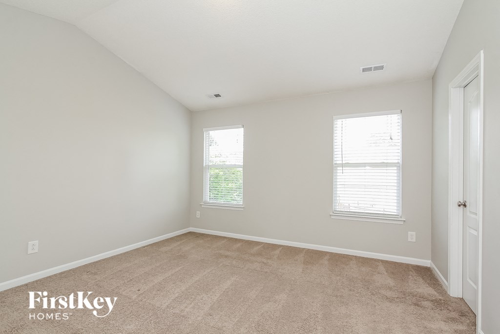 a bedroom with a carpeted floor and two windows