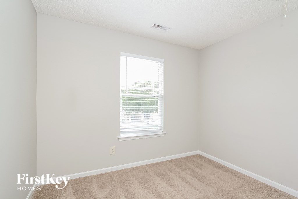 a bedroom with white walls and a window