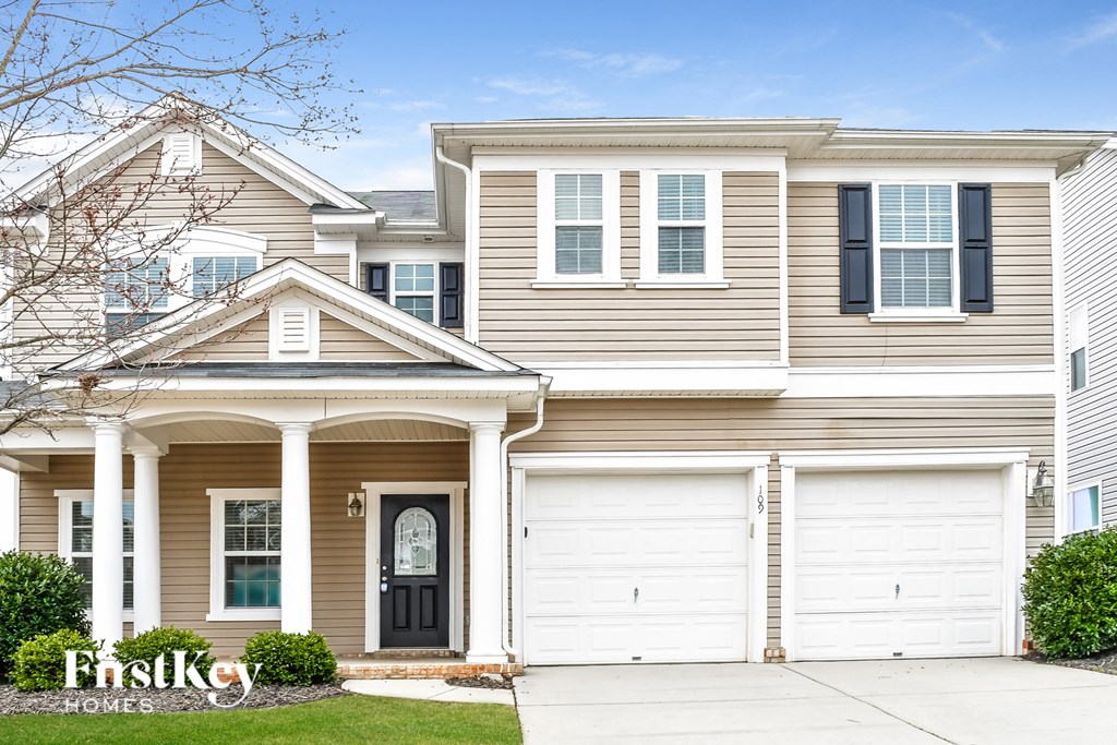 a beige house with two garage doors