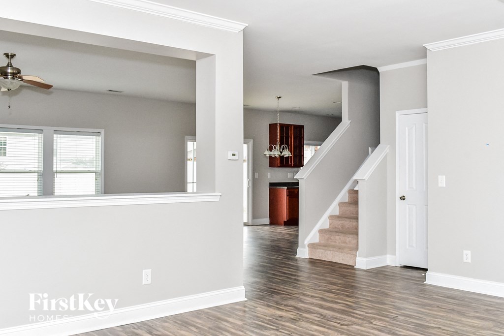 a renovated living room with a staircase and a dining room in the background