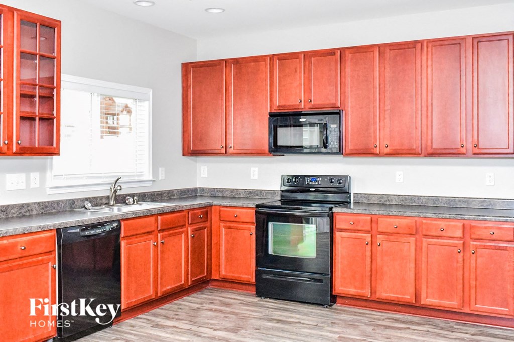 a kitchen with orange cabinets and black appliances and a sink