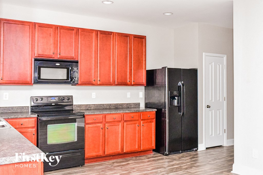 a kitchen with orange cabinets and a black refrigerator
