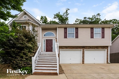 A two-story house with a red door and white garage doors.