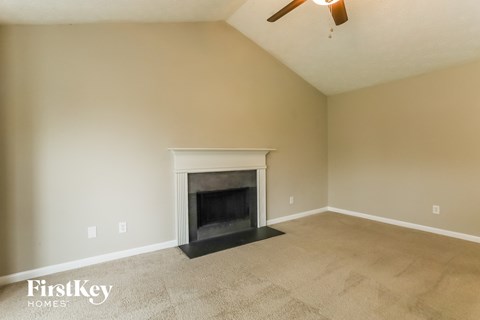 A living room with a fireplace and a fan on the ceiling.