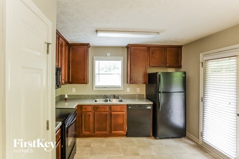 A kitchen with wooden cabinets and a black refrigerator.