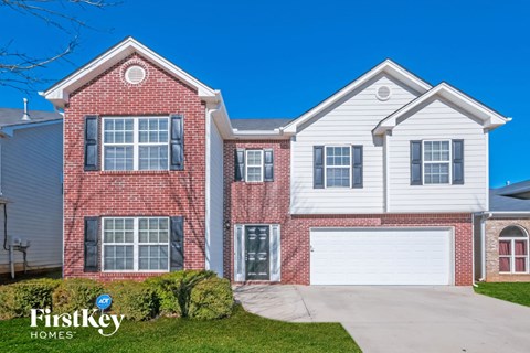 A two-story house with a red brick exterior and a white garage door.