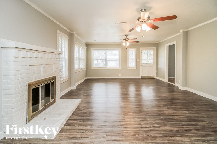 A spacious room with a fireplace and wooden floors.