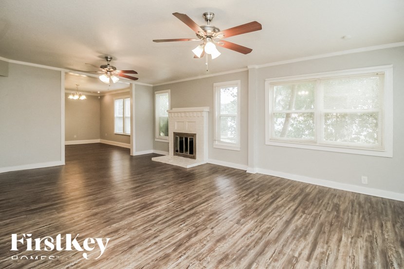 A spacious room with wood flooring and a ceiling fan.