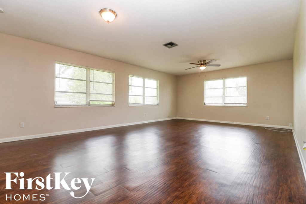 A spacious room with wooden floors and a ceiling fan.