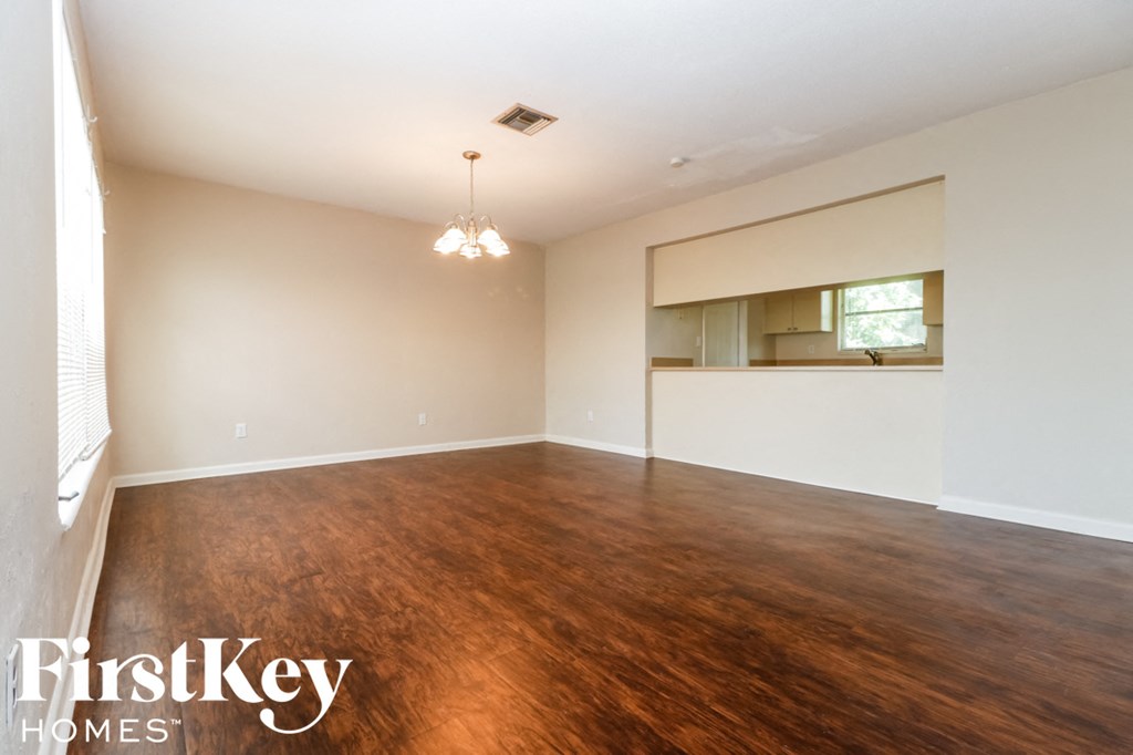 A room with wooden floors and a chandelier hanging from the ceiling.
