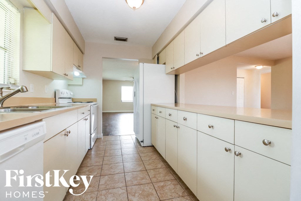 A kitchen with white cabinets and a tiled floor.