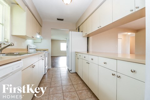 A kitchen with white cabinets and a tiled floor.
