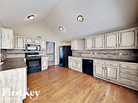 A kitchen with wooden floors and white cabinets.