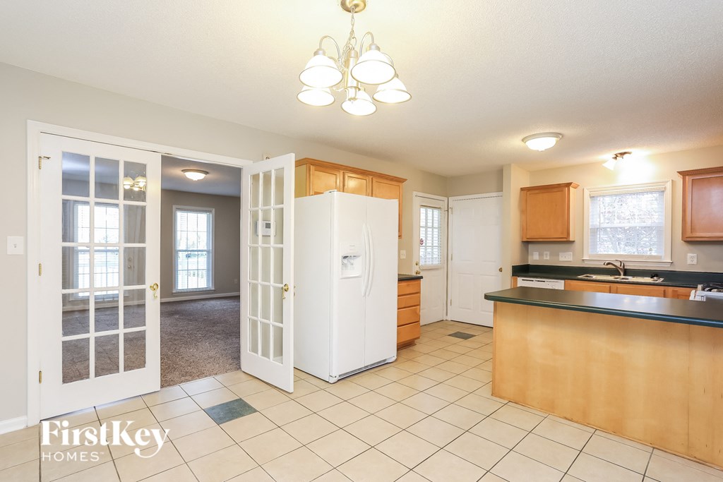 A kitchen with a refrigerator, sink, and cabinets.