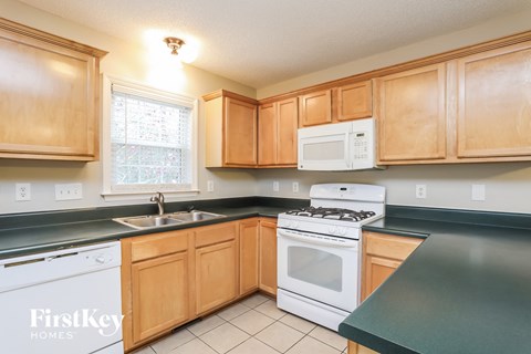 A kitchen with wooden cabinets and a white stove top oven.