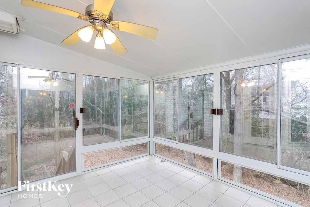 A sunny room with a ceiling fan and sliding glass doors.