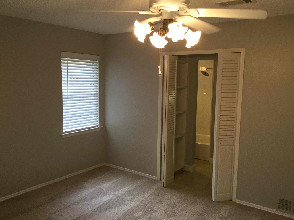 an empty bedroom with a ceiling fan and a closet