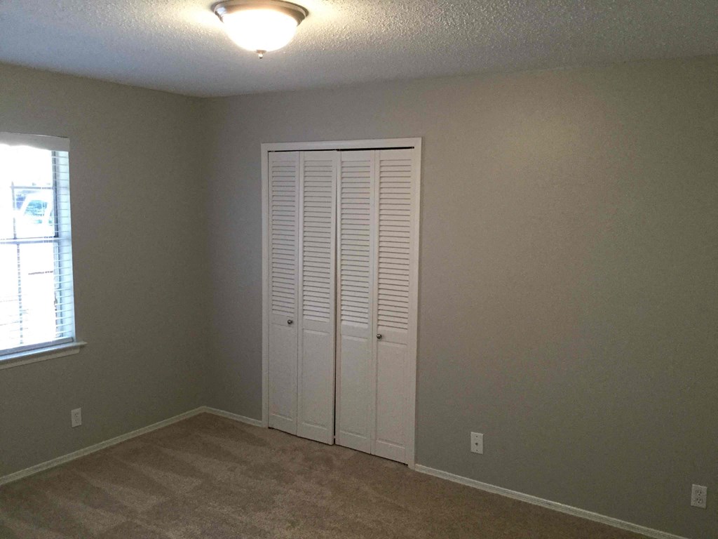 an empty room with a closet and a window