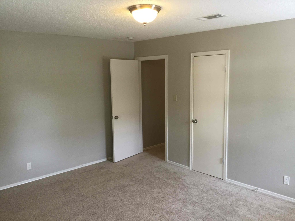 an empty room with a carpeted floor and two doors
