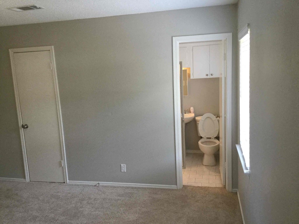 an empty room with a toilet and a door to a bathroom