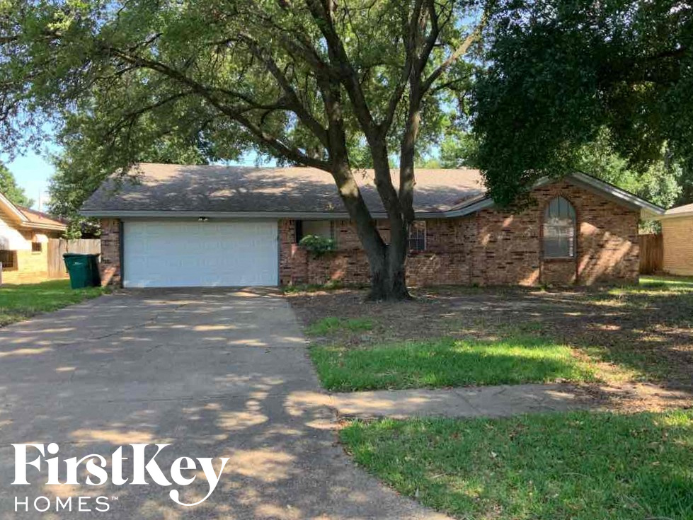 a brick house with a garage and a tree
