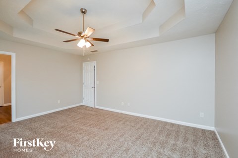 the spacious living room with ceiling fan and carpet