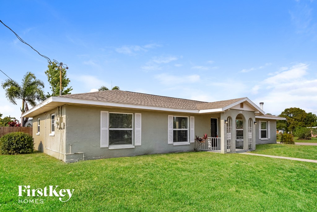 a small gray house with a yard and a lawn