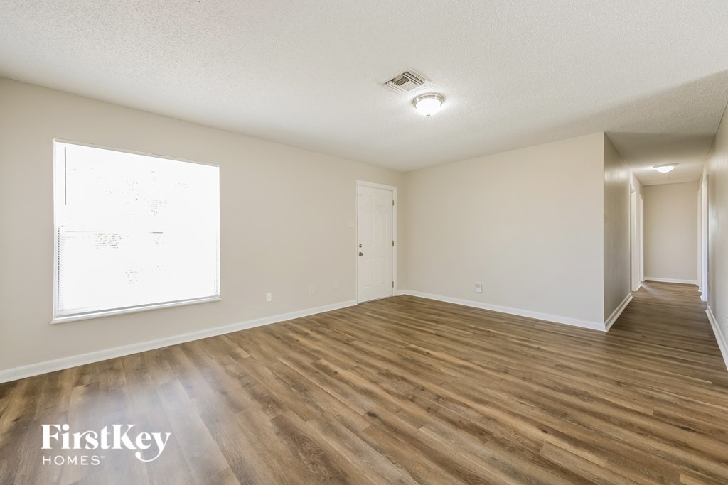 a spacious living room with hardwood flooring and a window
