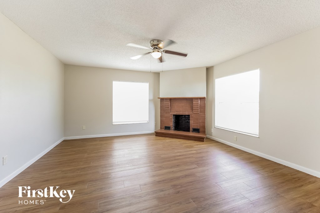 an empty living room with wood floors and a fireplace