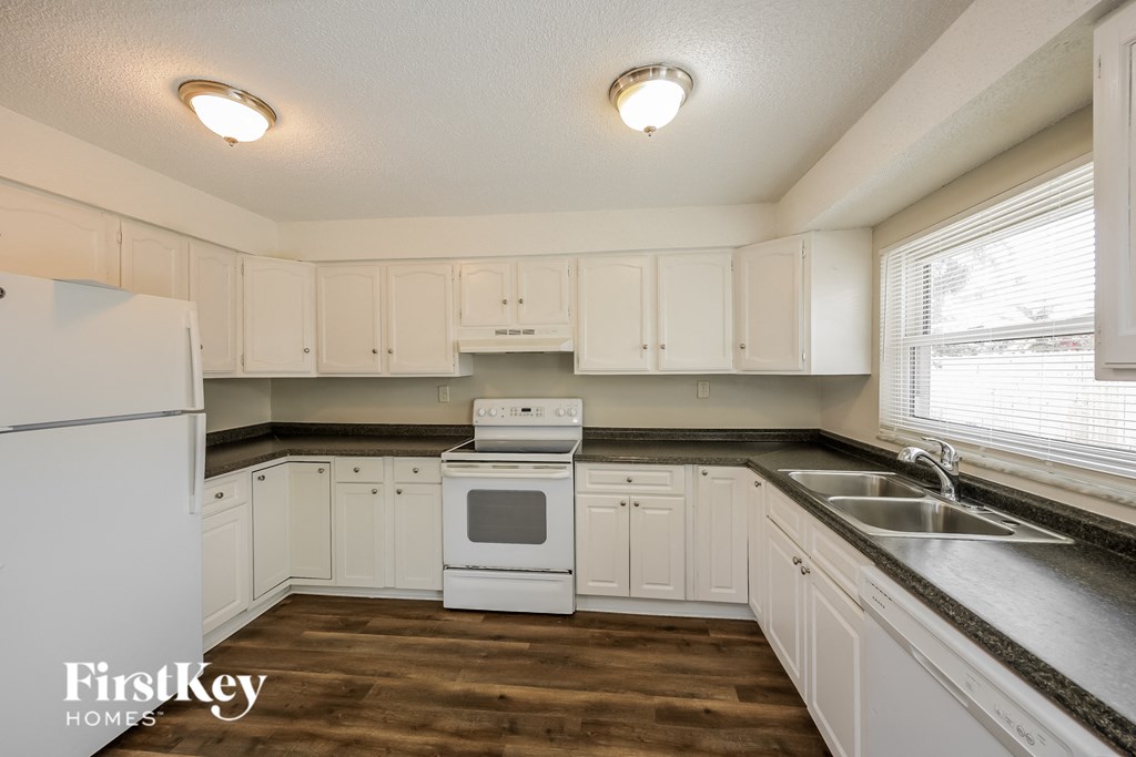 a kitchen with white cabinets and white appliances and a sink